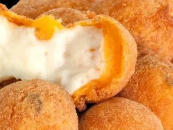 Mini salgados fritos, um deles aberto com queijo derretido